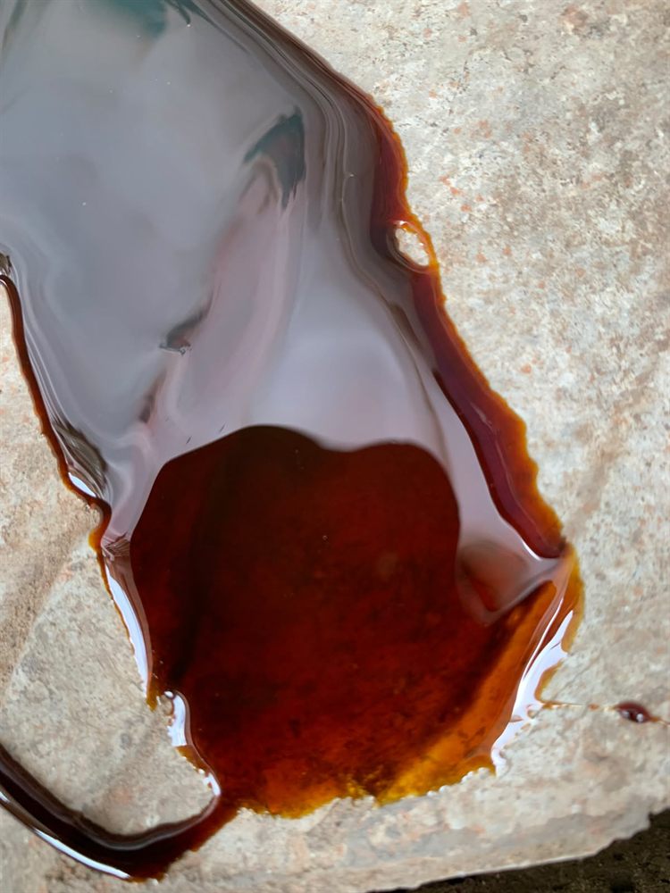 Premium Grade A cane molasses for cattle feed — the characteristic dark amber to near-black colour, glossy surface, and slow viscous flow that indicate high Brix and binding strength