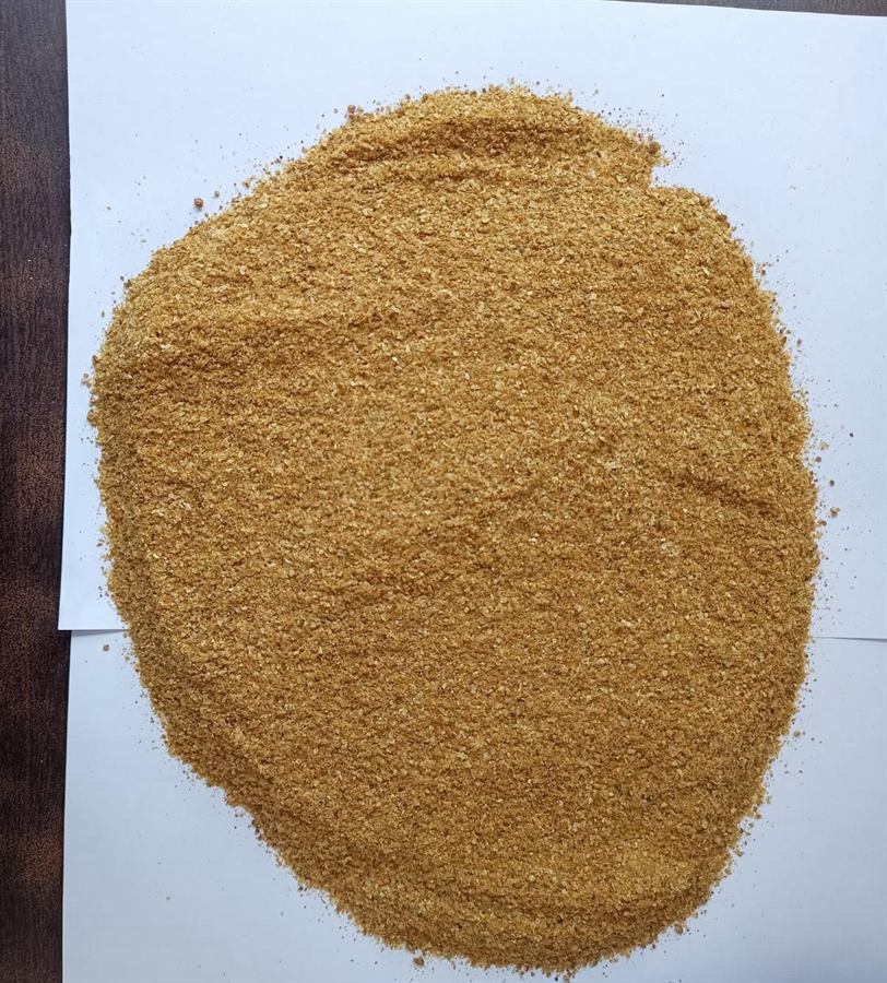 Brown flake-like Rice DDGS on a white paper background